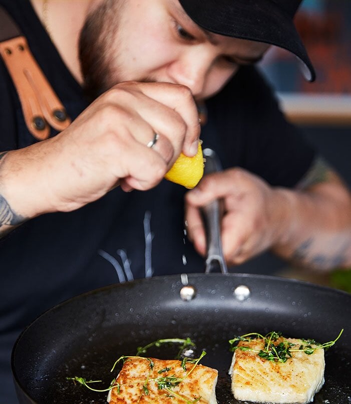 الطاهي يطهو سمكة الفحم في مقلاة